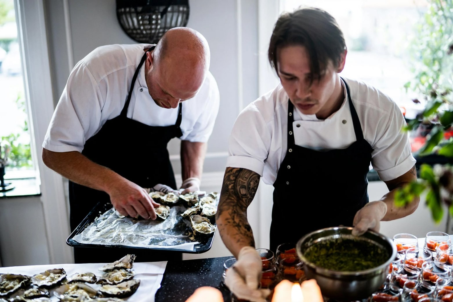 Two chefs arranging appetizers at a food preparation counter.