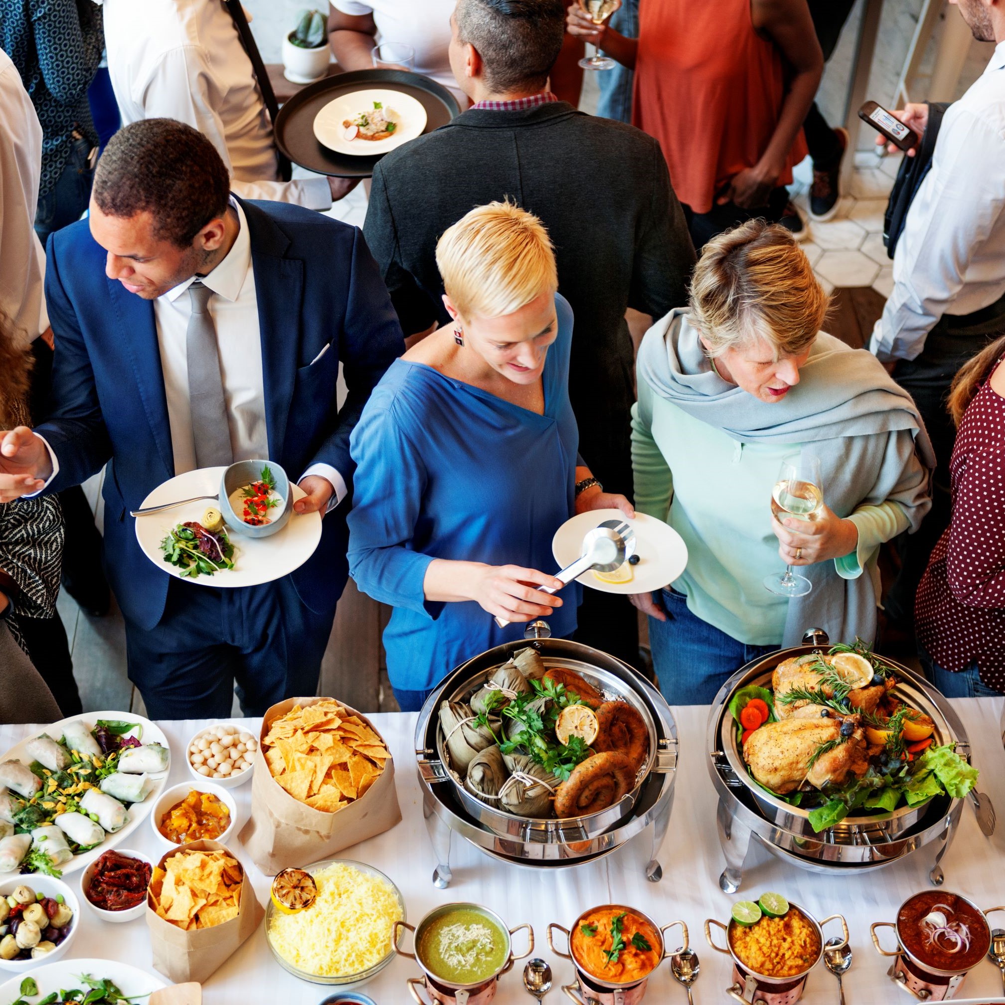 Guests choosing dishes from a buffet of hot food, salads, and sides.