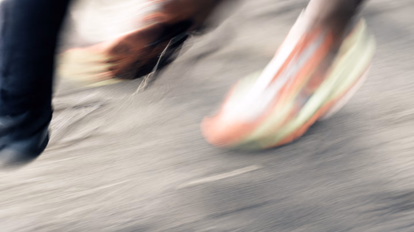 Deux pieds en mouvement, flou de mouvement, avec une chaussure de sport colorée sur un sol gris.