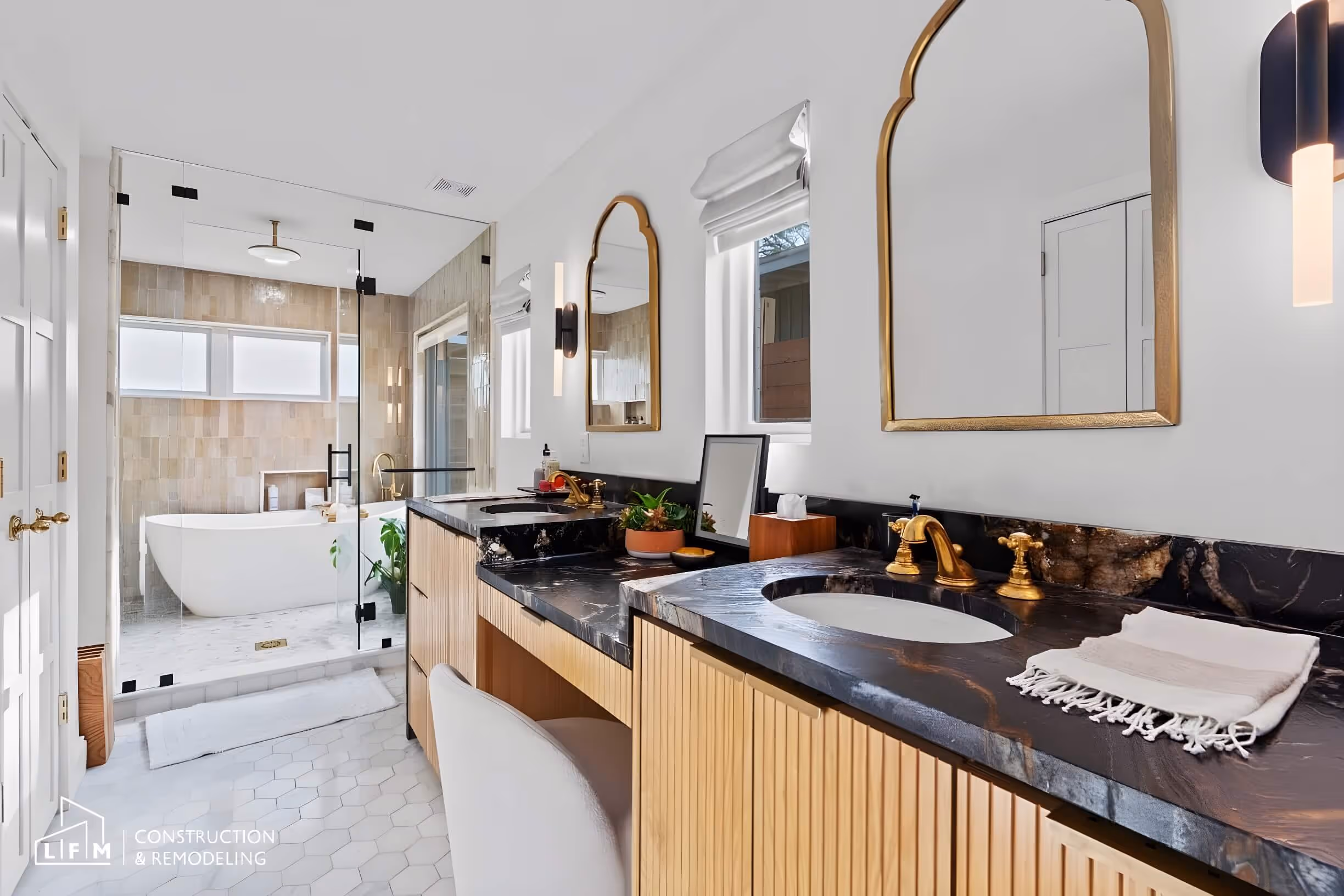 Modern bathroom with wood accents, black countertop, dual sinks, and standalone tub in Austin.