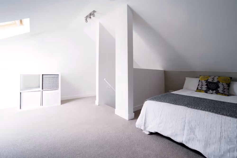 Minimalist attic bedroom with white decor, shelf, and bed.