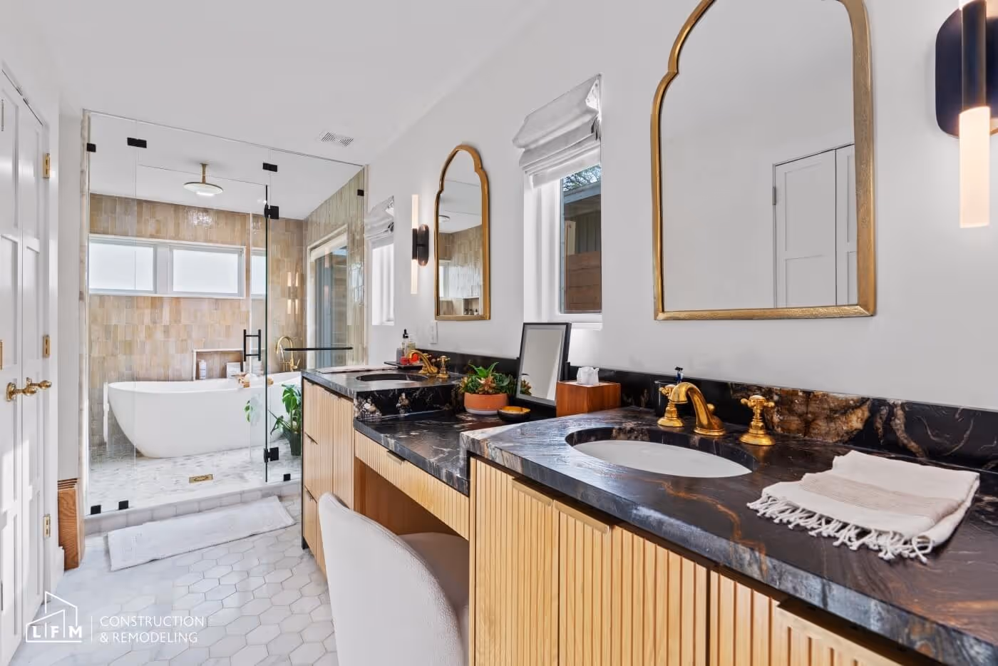 Modern bathroom with wood vanity, black countertop, free-standing tub, and walk-in shower.