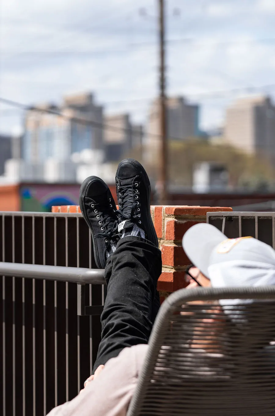 Man in hat with feet propped up on balcony railing enjoys Atlanta skyline from Local's offices