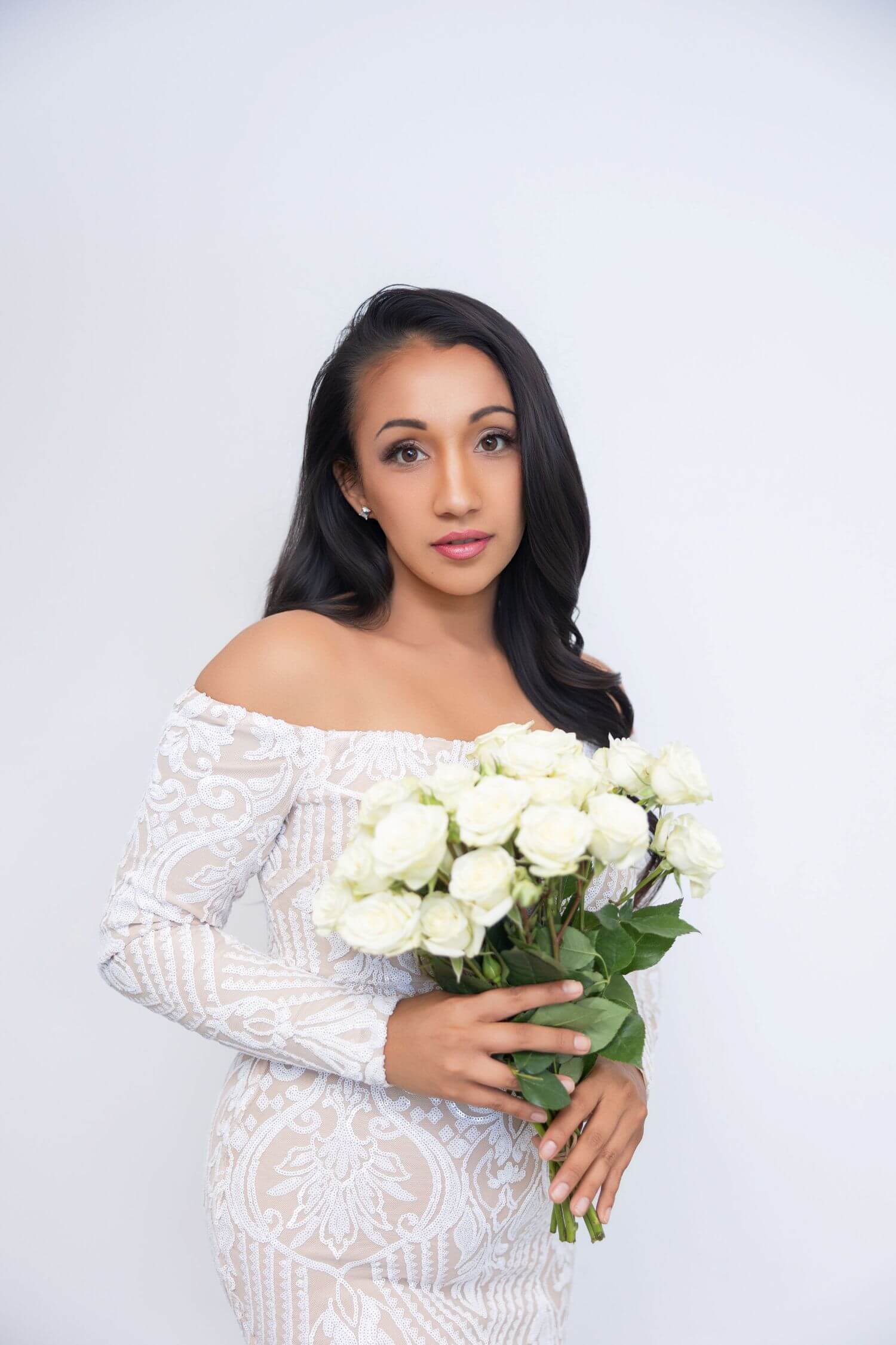 Young bride in wedding dress, holding white bouquet.