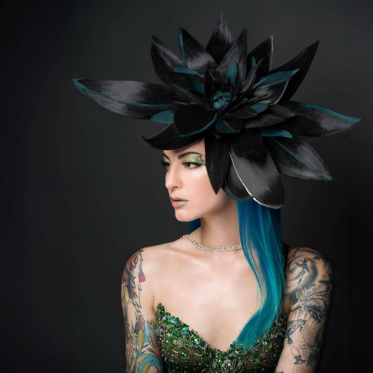 Whitley Queen in green jeweled dress with a large black and green floral hat.