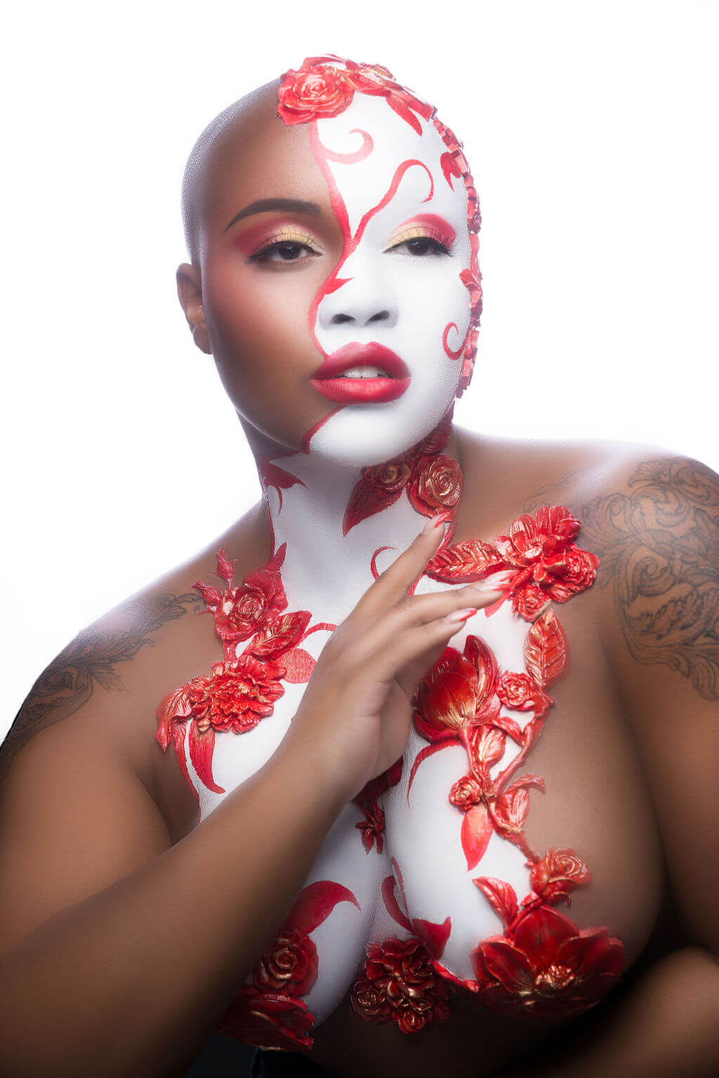 Young black woman with half face and chest painted white, with red flowers.