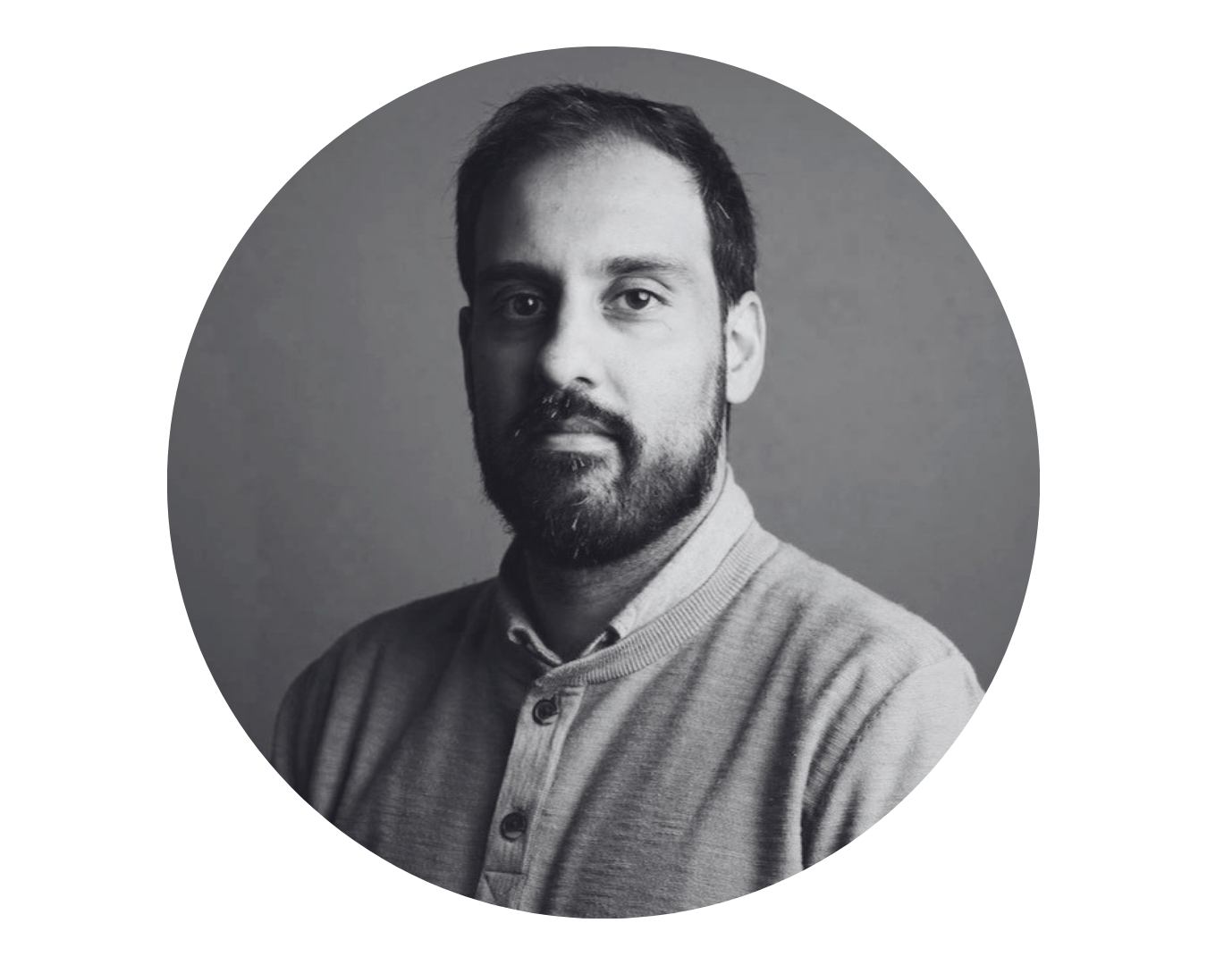 Black and white portrait of a bearded man wearing a buttoned sweater facing the camera.