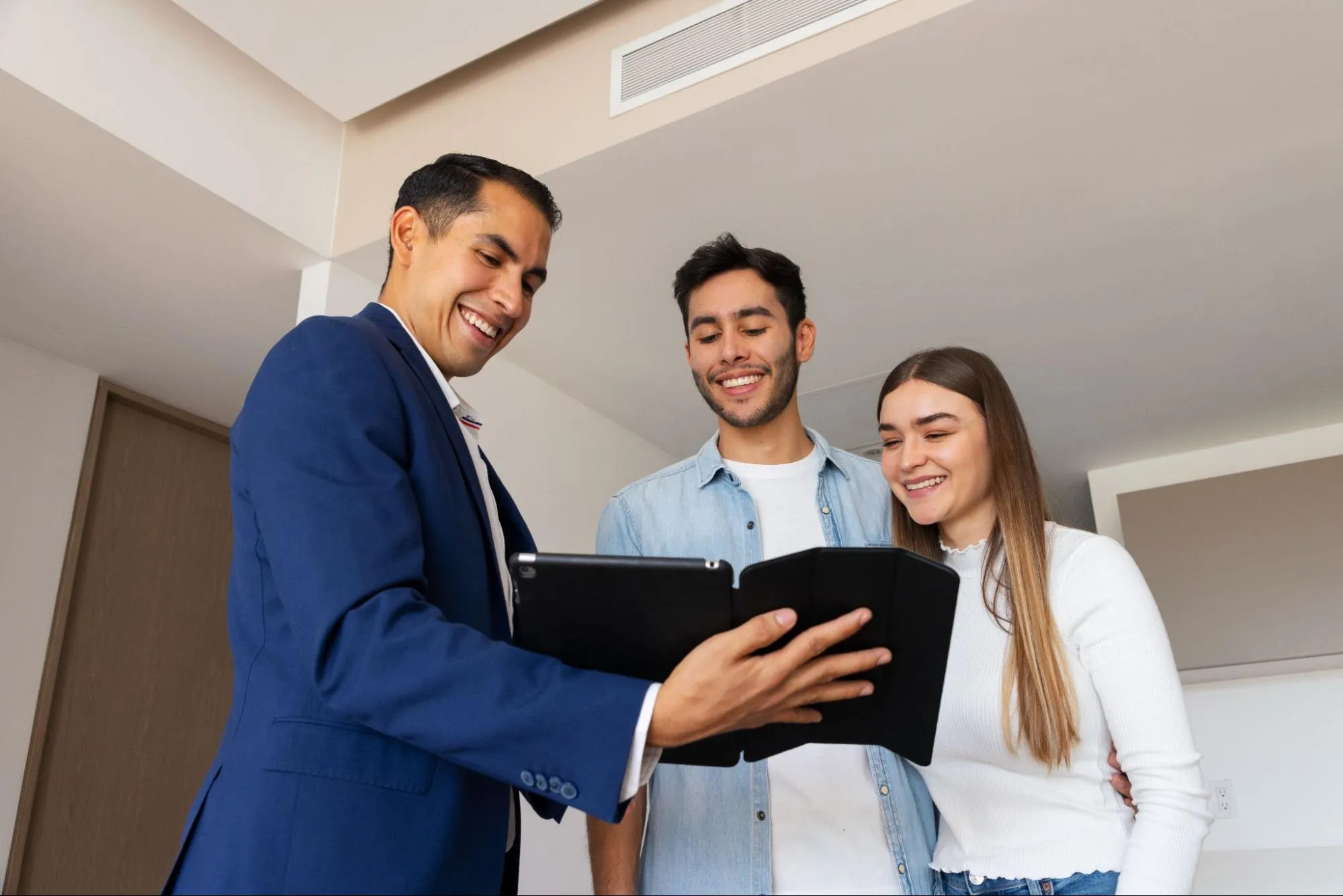 A real estate agent showing property to a couple on a tablet.