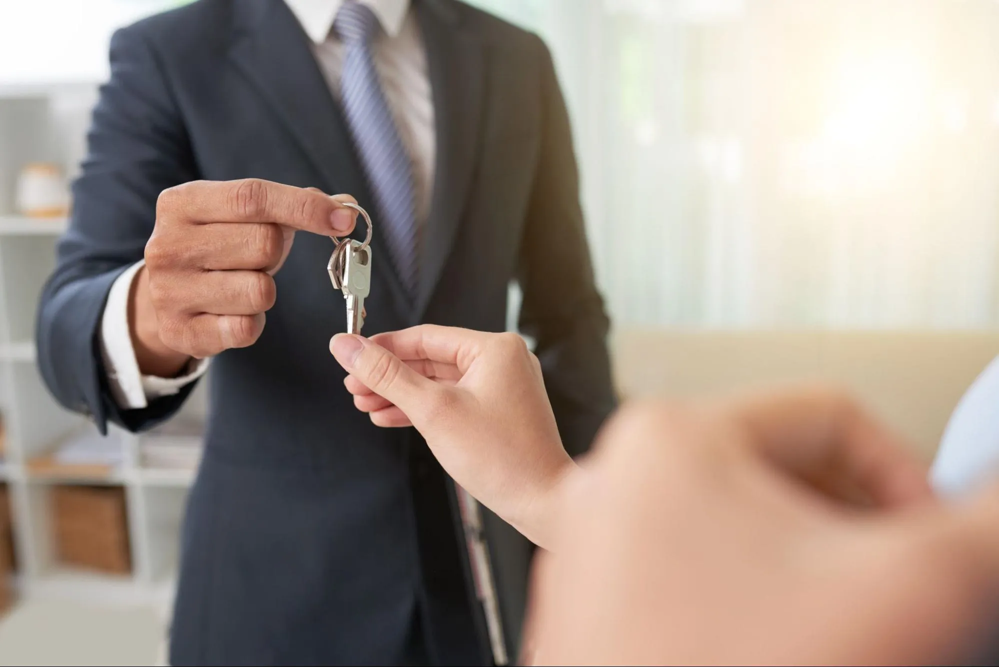 Broker handing the house keys to the person who bought the house.