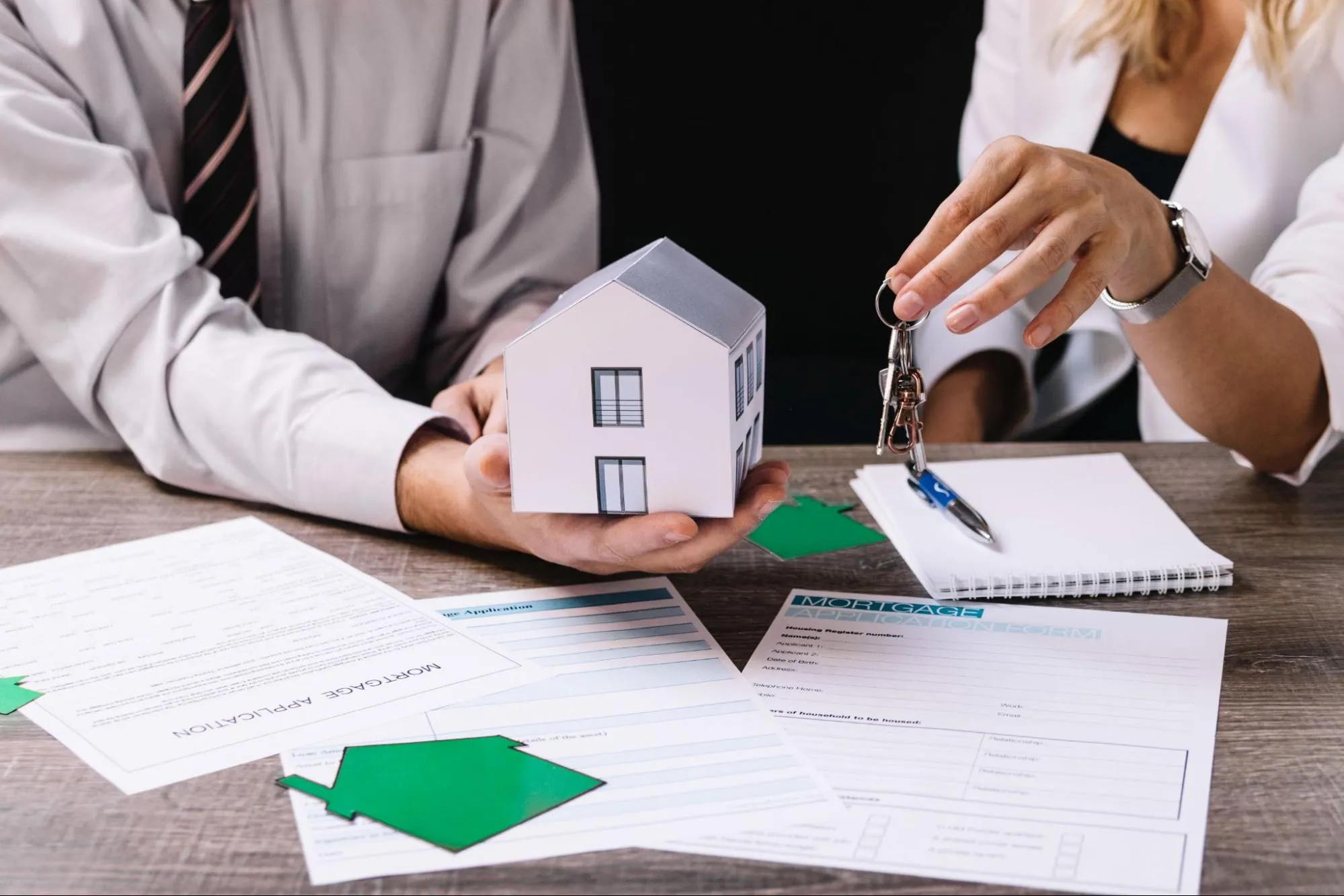 Realtor handing keys to the new owner with paperwork spread out on the table.