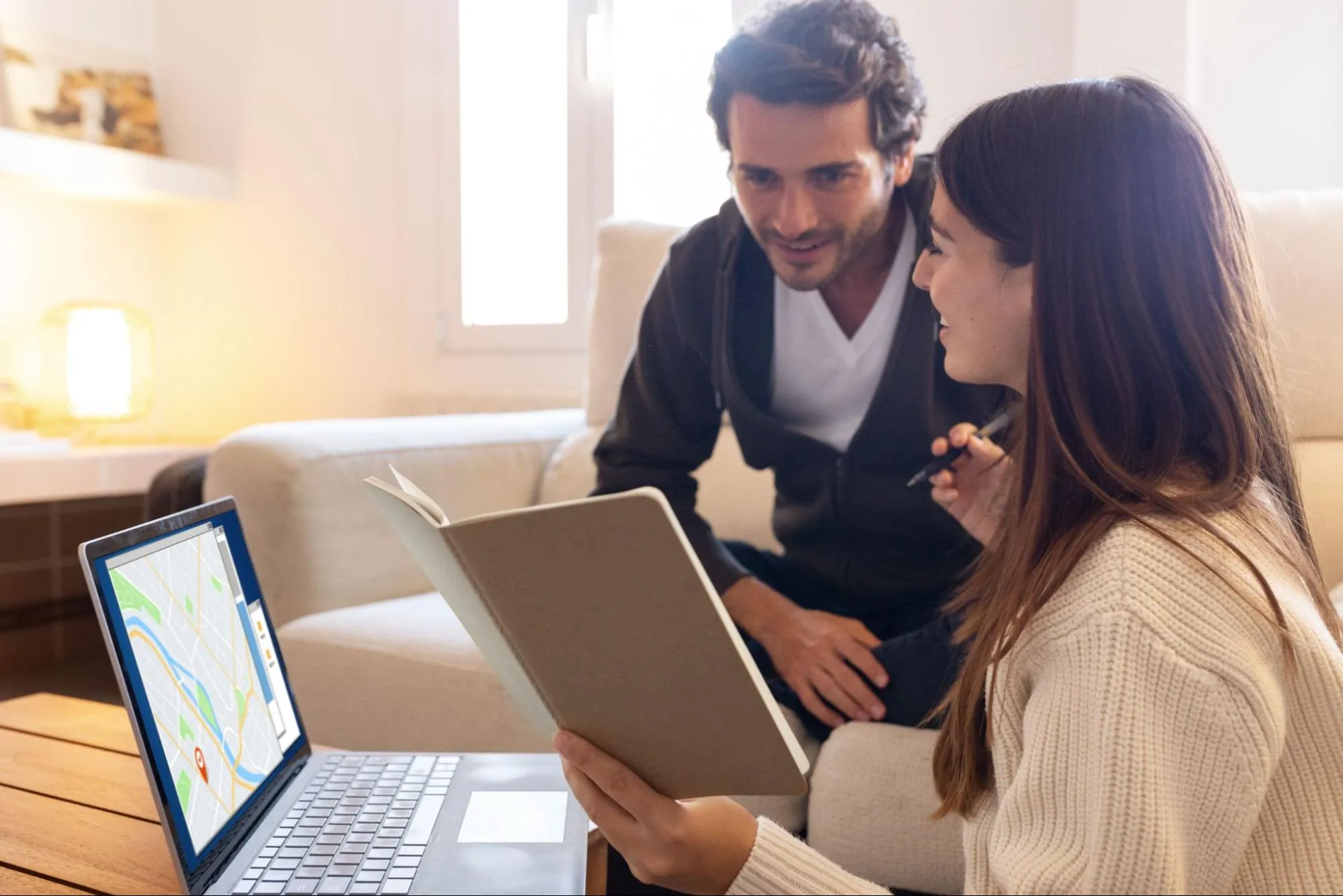 Two people researching how much to invest in real estate with a laptop and a notebook.