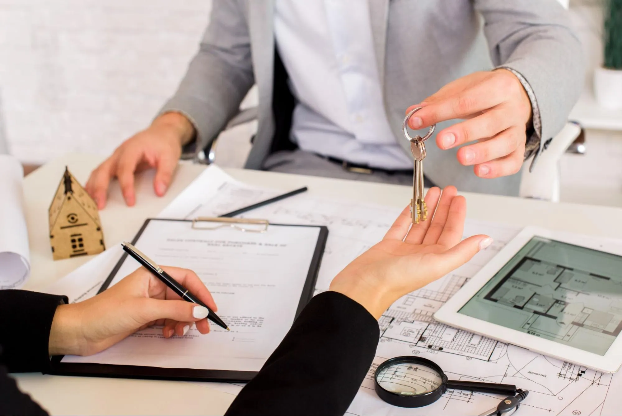 A broker giving keys to the new homeowner as they sign the paperwork.