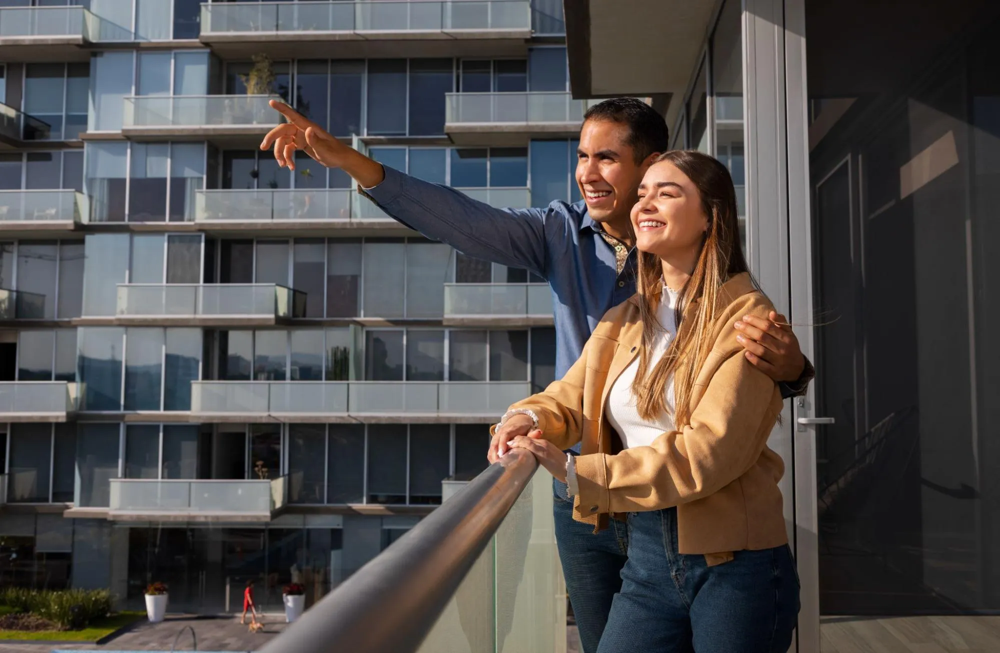 A happy couple looking out of the balcony of their new home.