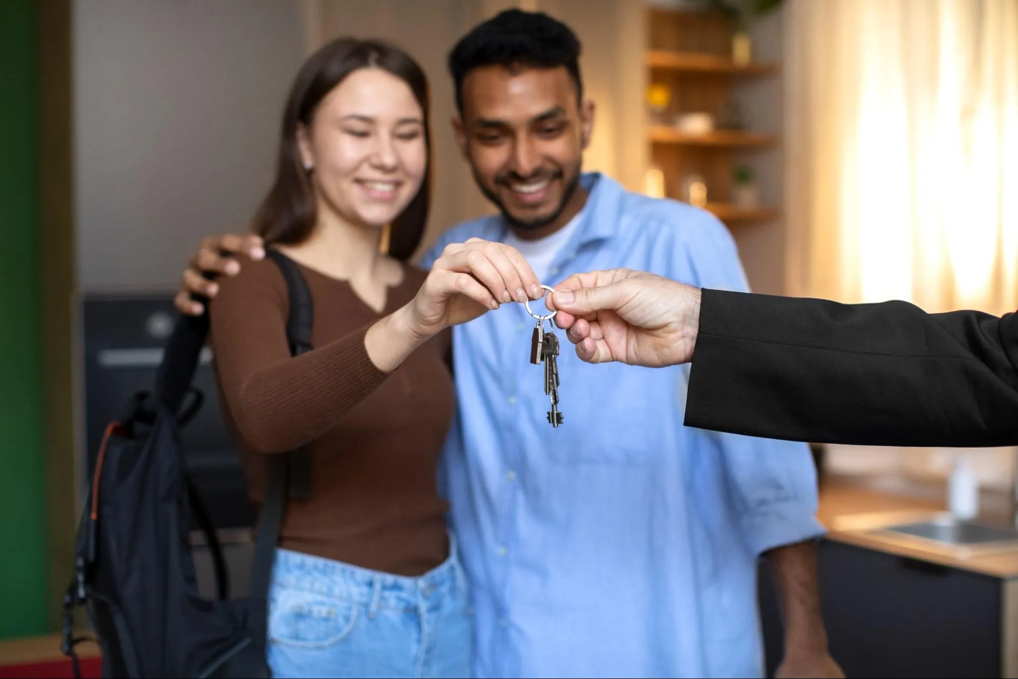 A real estate broker hands over the key to a new house to a young couple.