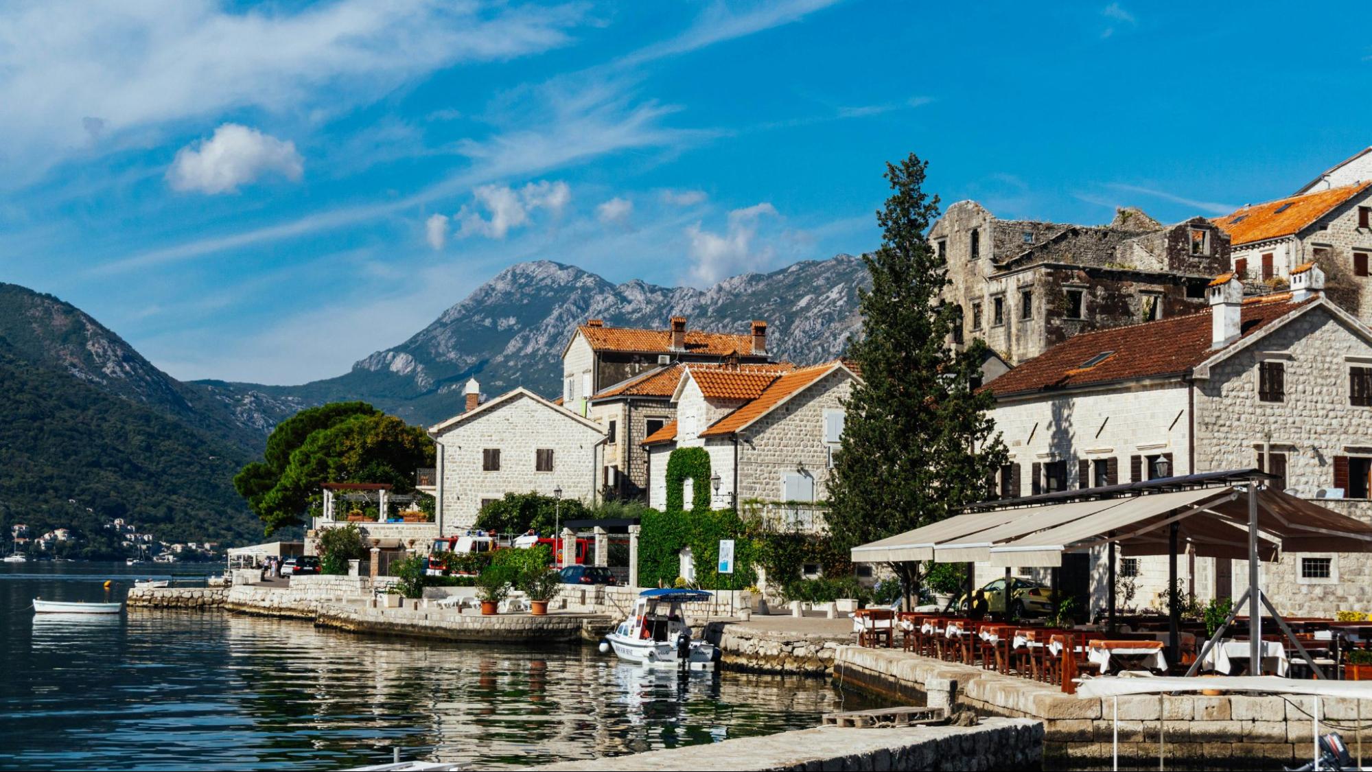 Beautiful shot of a coast in Perast with buildings, boats, and restaurants.