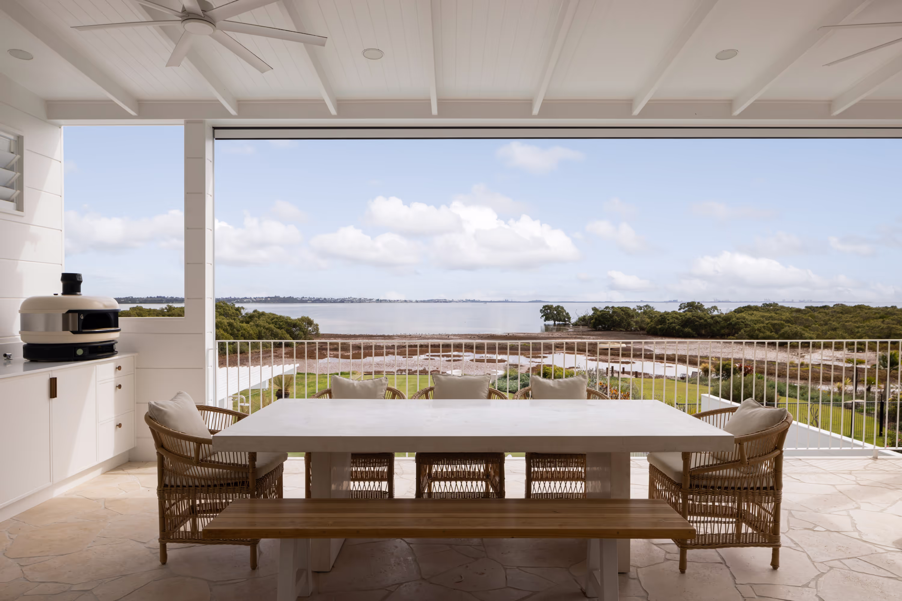 Covered outdoor living area in beach style home plan overlooking coastal landscape