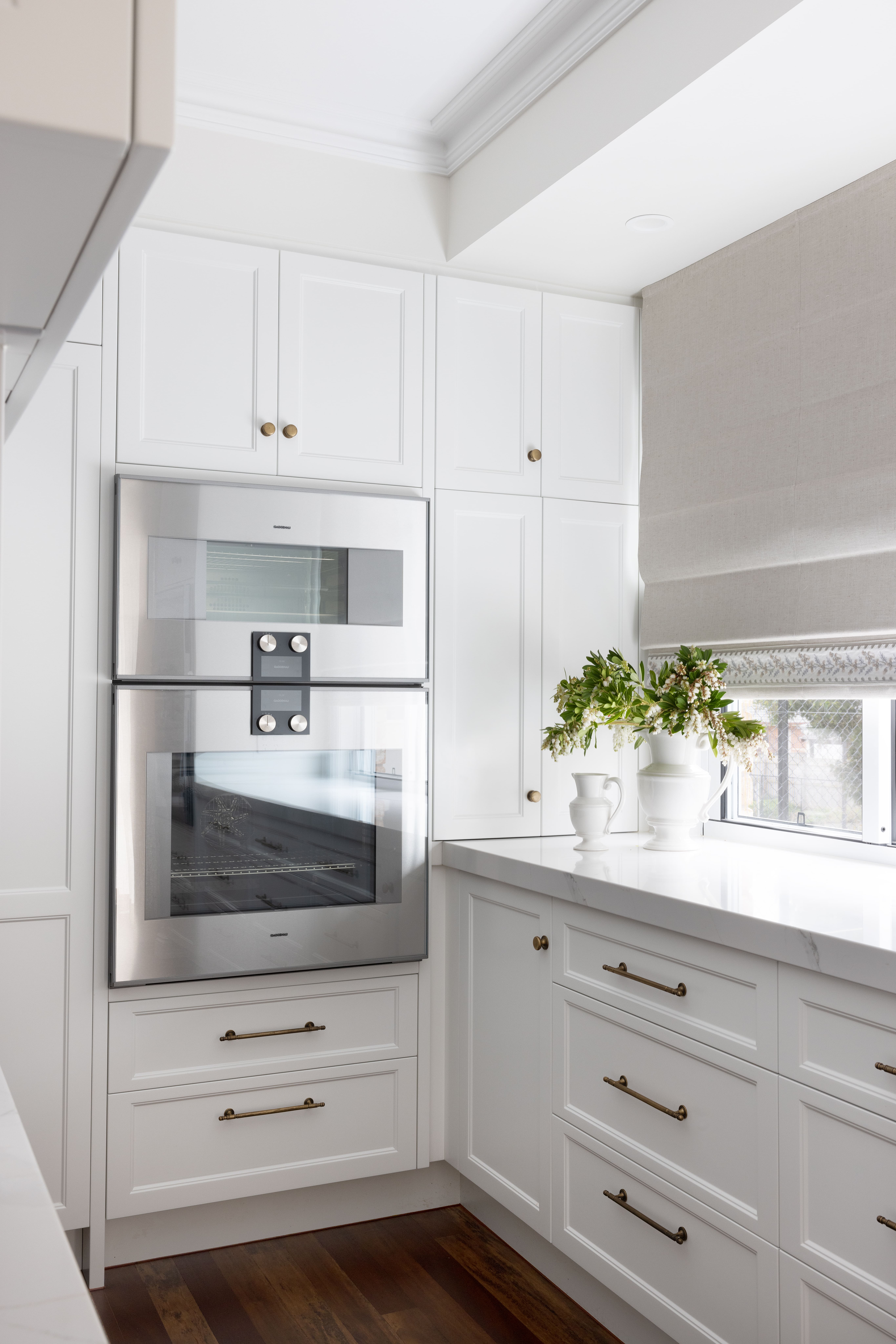 Kitchen close-up with shaker cabinetry, stone bench and dual ovens 