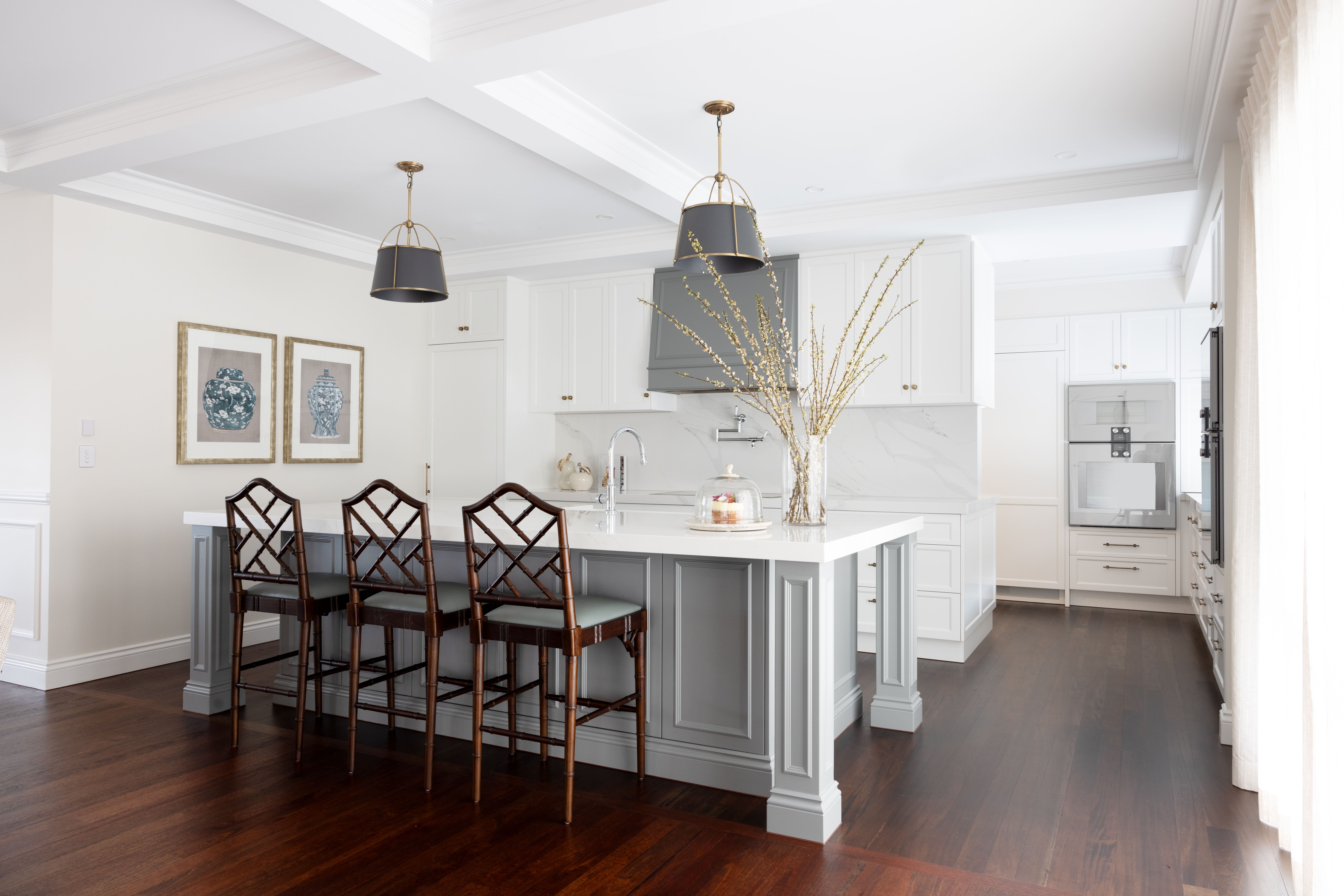 Kitchen with custom cabinetry and two feature lights over the island with brass touches