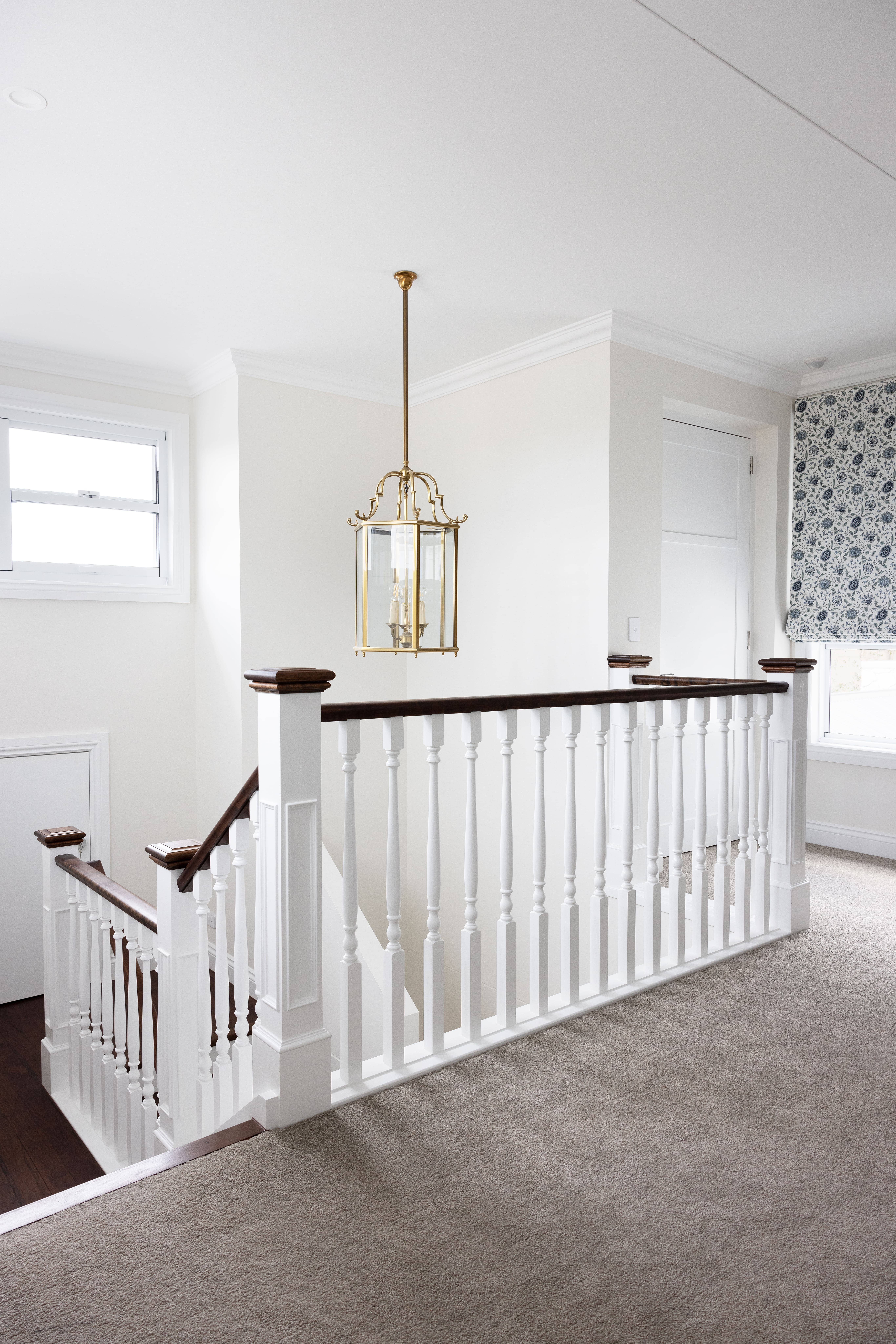 Staircase with timber treads, white balustrades, and pendant light
