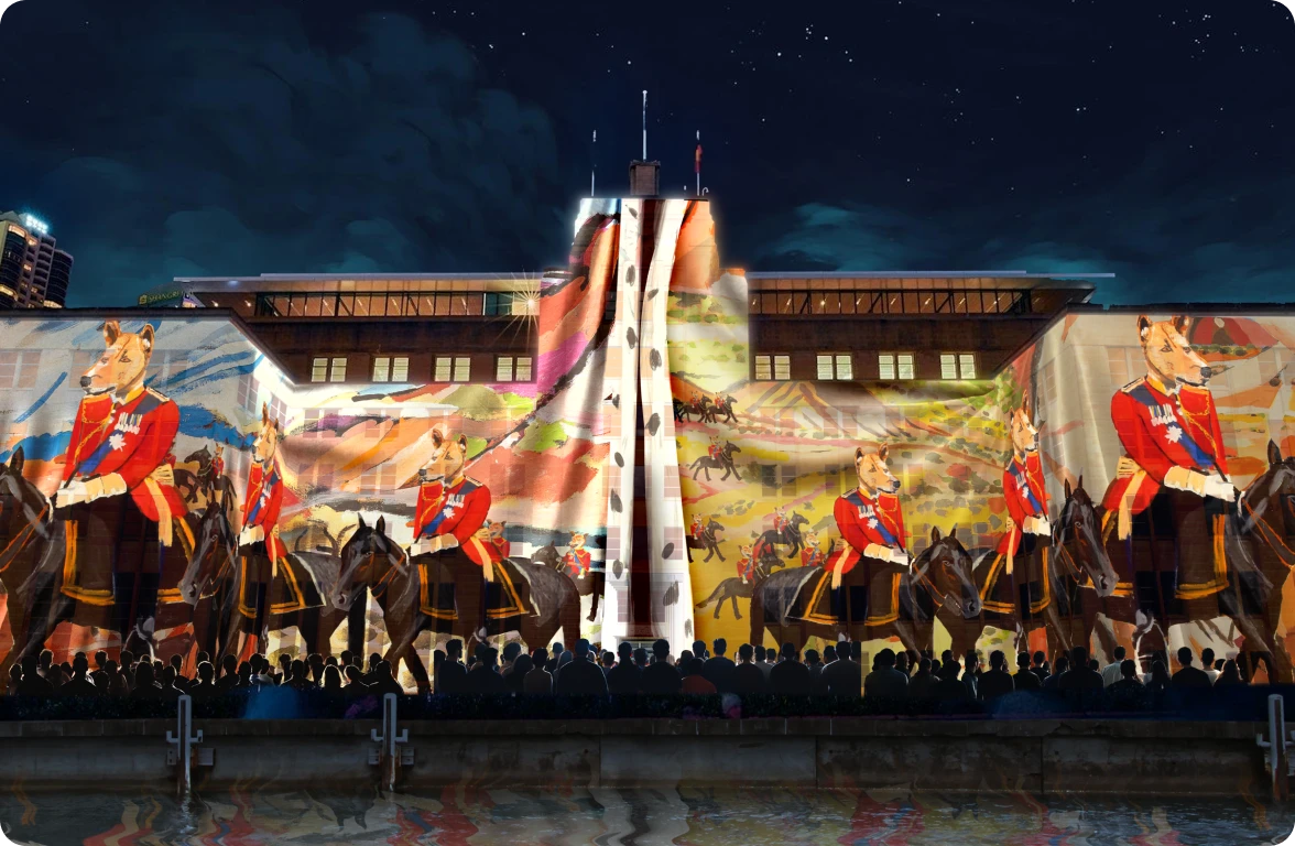 Crowd watching a large-scale projection artwork on the façade of the Museum of Contemporary Art Australia, featuring Vincent Namatjira’s painting of uniformed dingoes on horseback, presented during Vivid Sydney 2025.