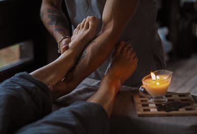Massage des pieds lors d’une séance de réflexologie thaïlandaise, technique ancestrale de stimulation plantaire.
