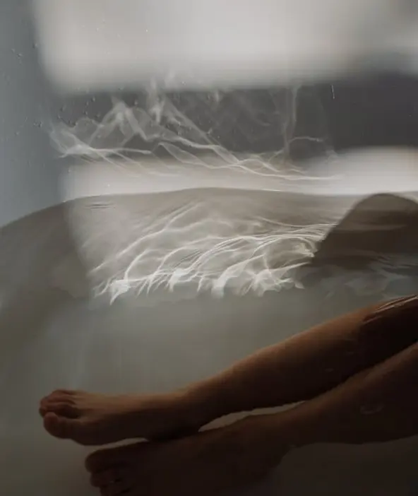Jambes immergées dans un bain chaud, source de relaxation et de soulagement des tensions.
