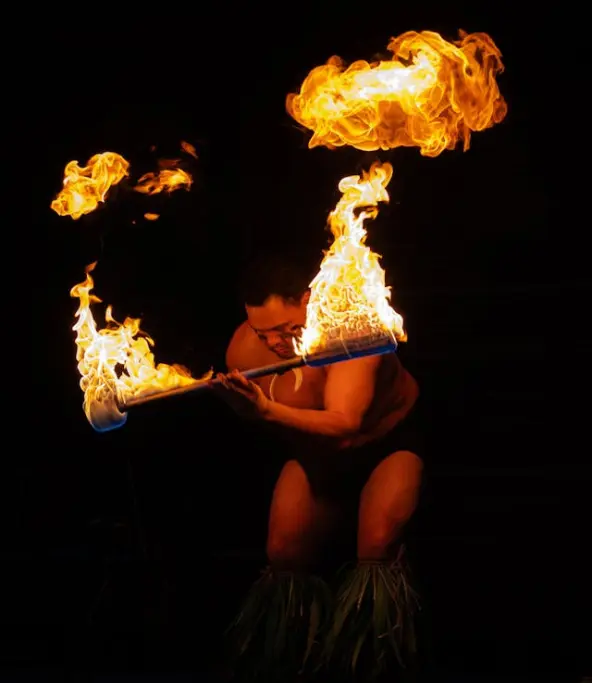 Danse traditionnelle hawaïenne au feu, spectacle culturel avec danseurs en costumes typiques et torches enflammées.