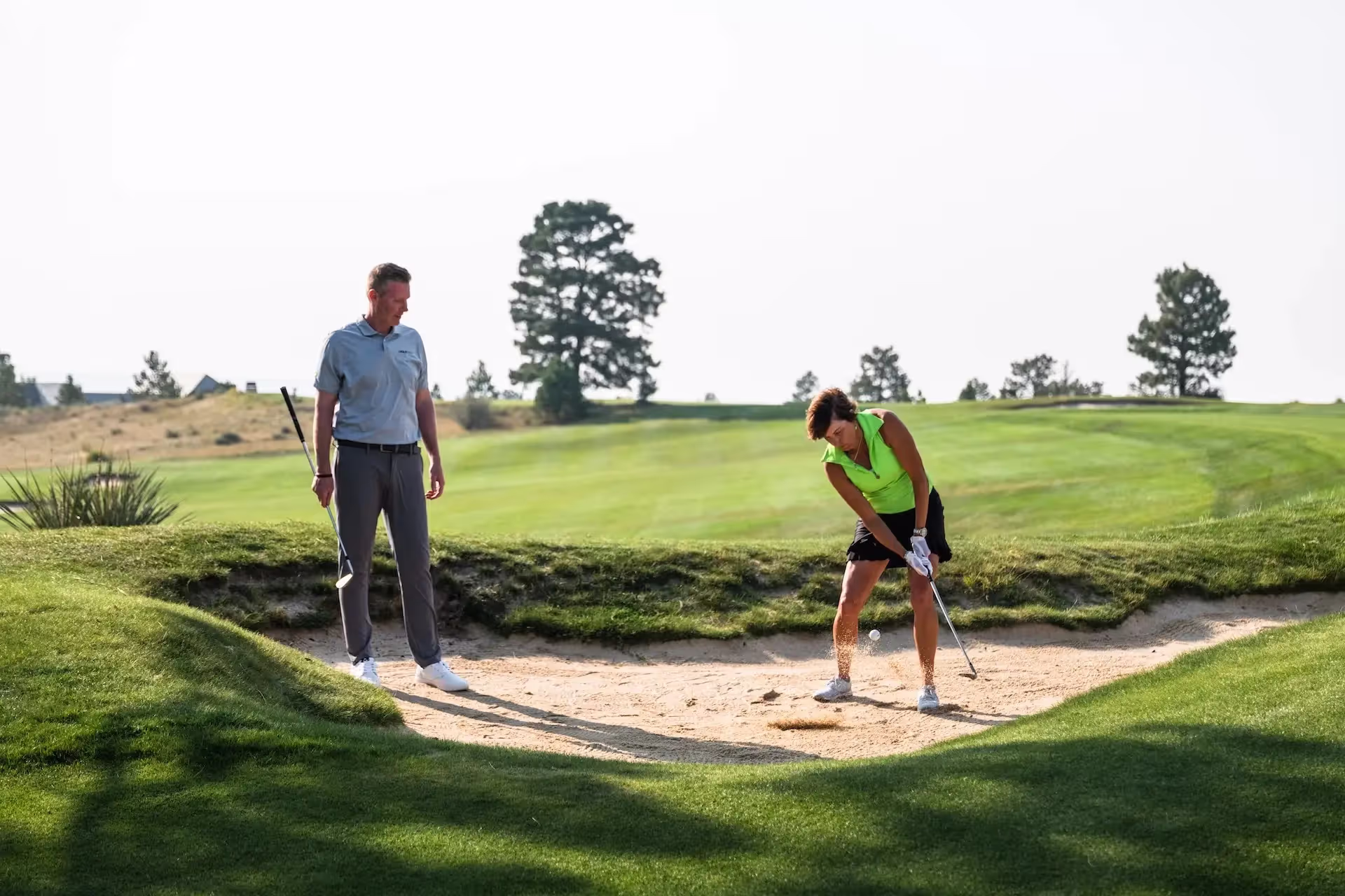 Student and coach practicing bunker shots on the course