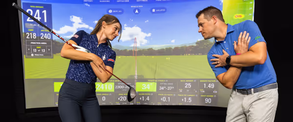 A GOLFTEC coach practicing drills with a student, focusing on technique during a lesson.