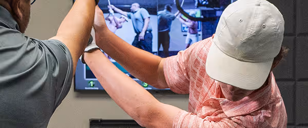 GOLFTEC coach guiding a student through their backswing during a lesson, providing hands-on instruction.