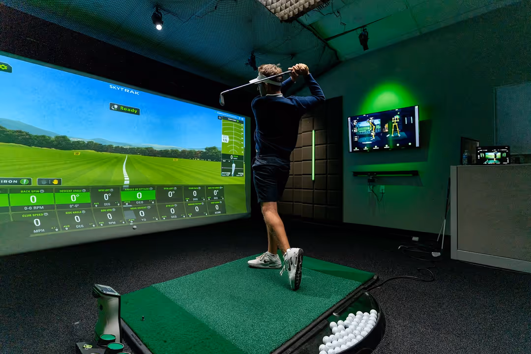 Man practicing his swing in a GOLFTEC golf simulator bay, using a simulator studio 