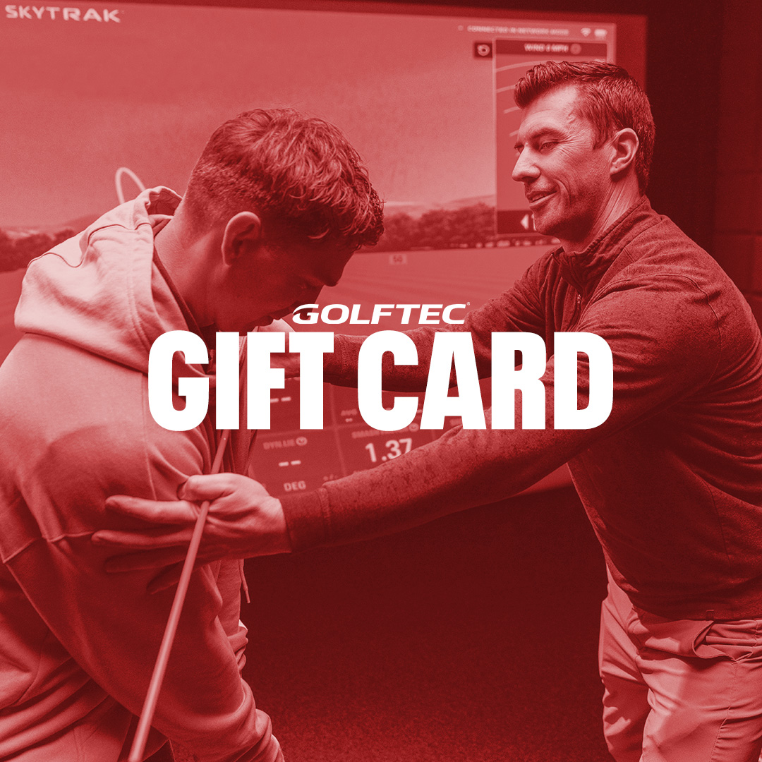 Golf instructor helping a student with swing posture in an indoor golf simulator with GOLFTEC gift card text overlay.
