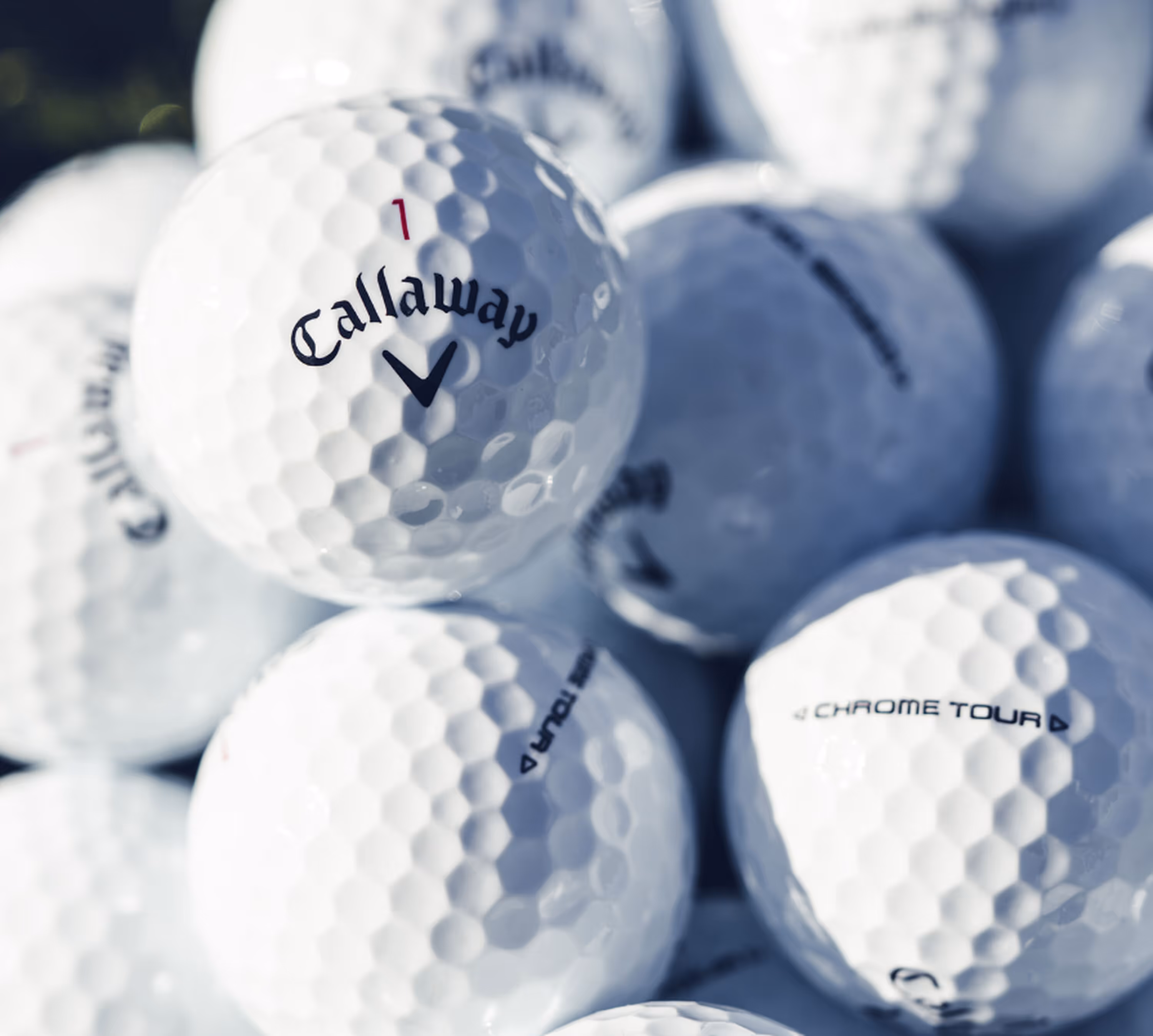 Close-up of several white Callaway Chrome Tour golf balls clustered together.