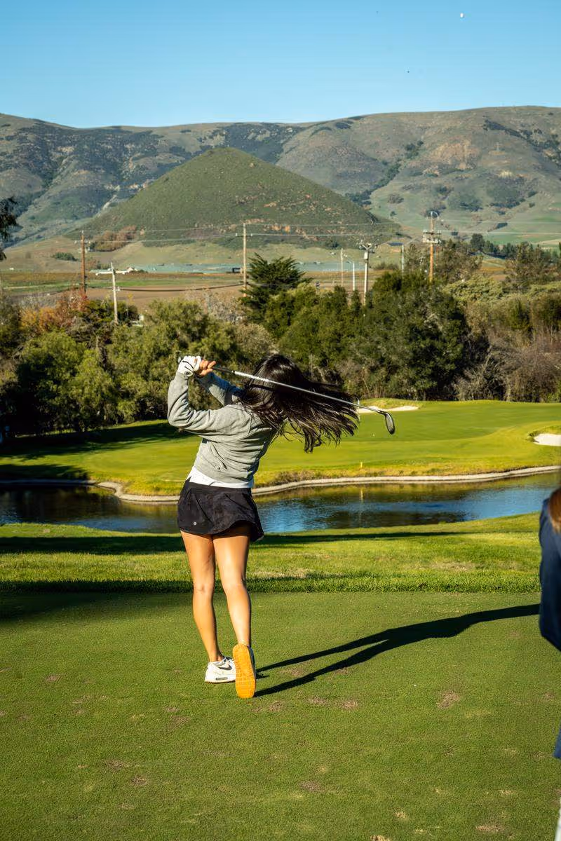 A female golfer executing a refined, biomechanically efficient swing during a GOLFTEC outdoor coaching session, demonstrating improved consistency and energy transfer.
