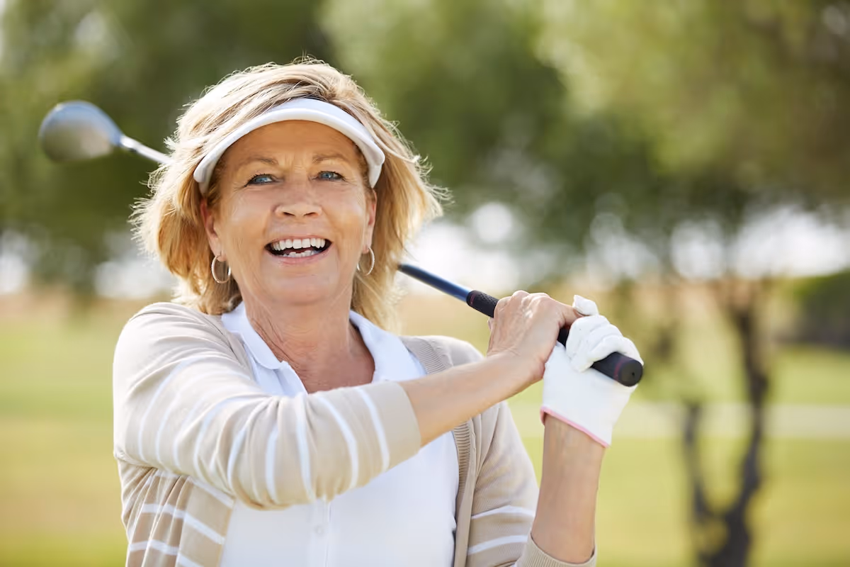 A confident female golfer practicing her swing during a professional GOLFTEC coaching session, emphasizing personalized performance training and biomechanical improvement for women golfers.