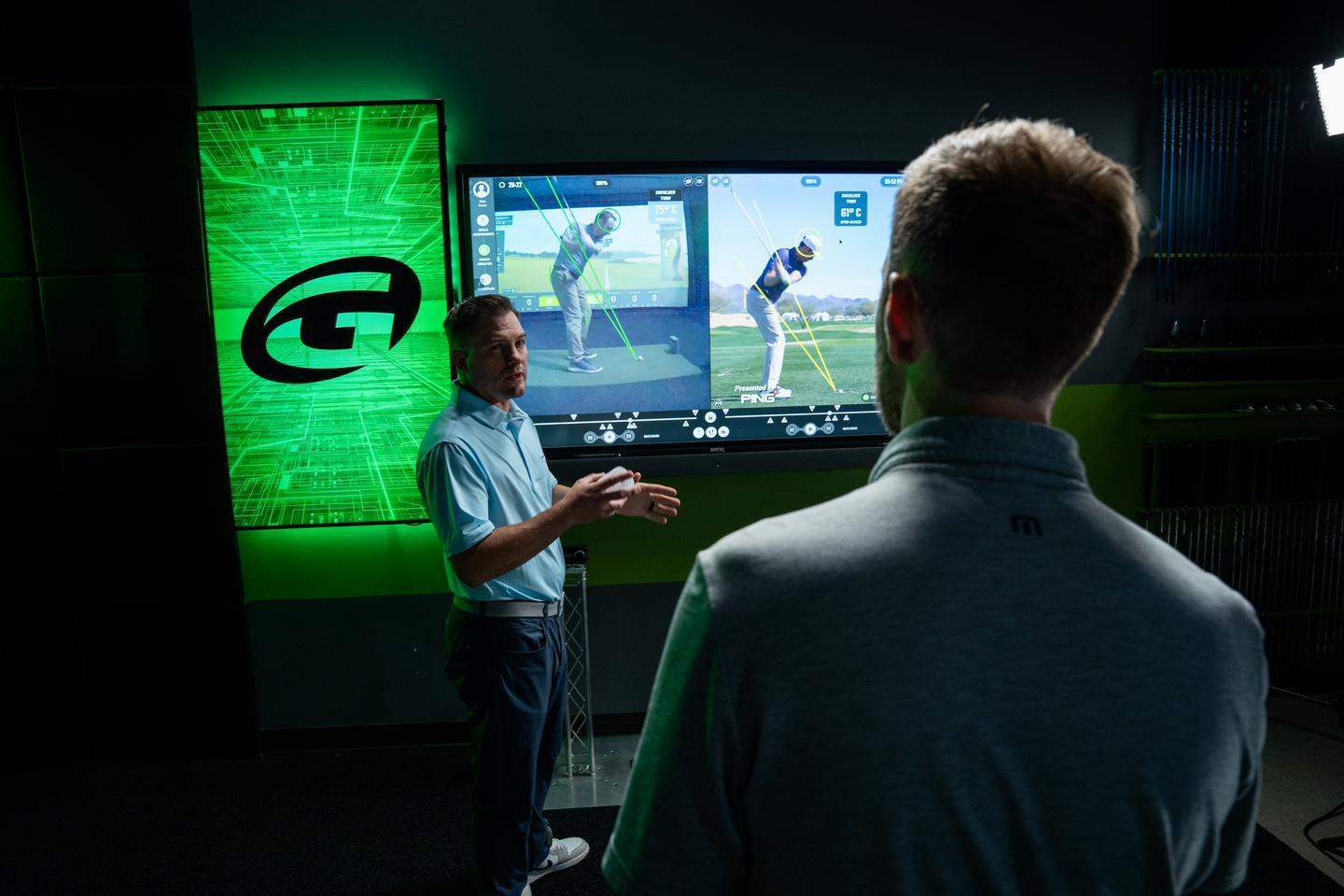 SKYTRAK indoor golf simulator studio setup with golfer viewing swing analysis on large projection screen — certified coach reviewing real-time launch monitor data and ball flight in a private SKYTRAK home simulator bay
