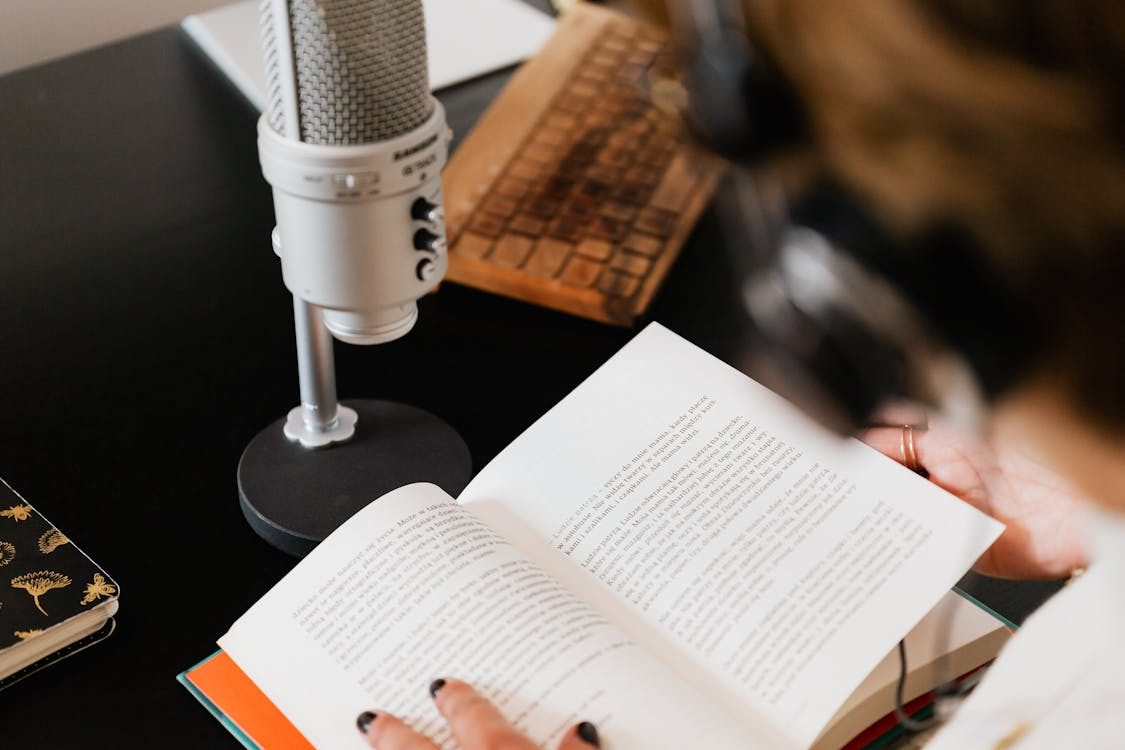 elder female author being interviewed on a podcast with microphone and headphones, promoting a book