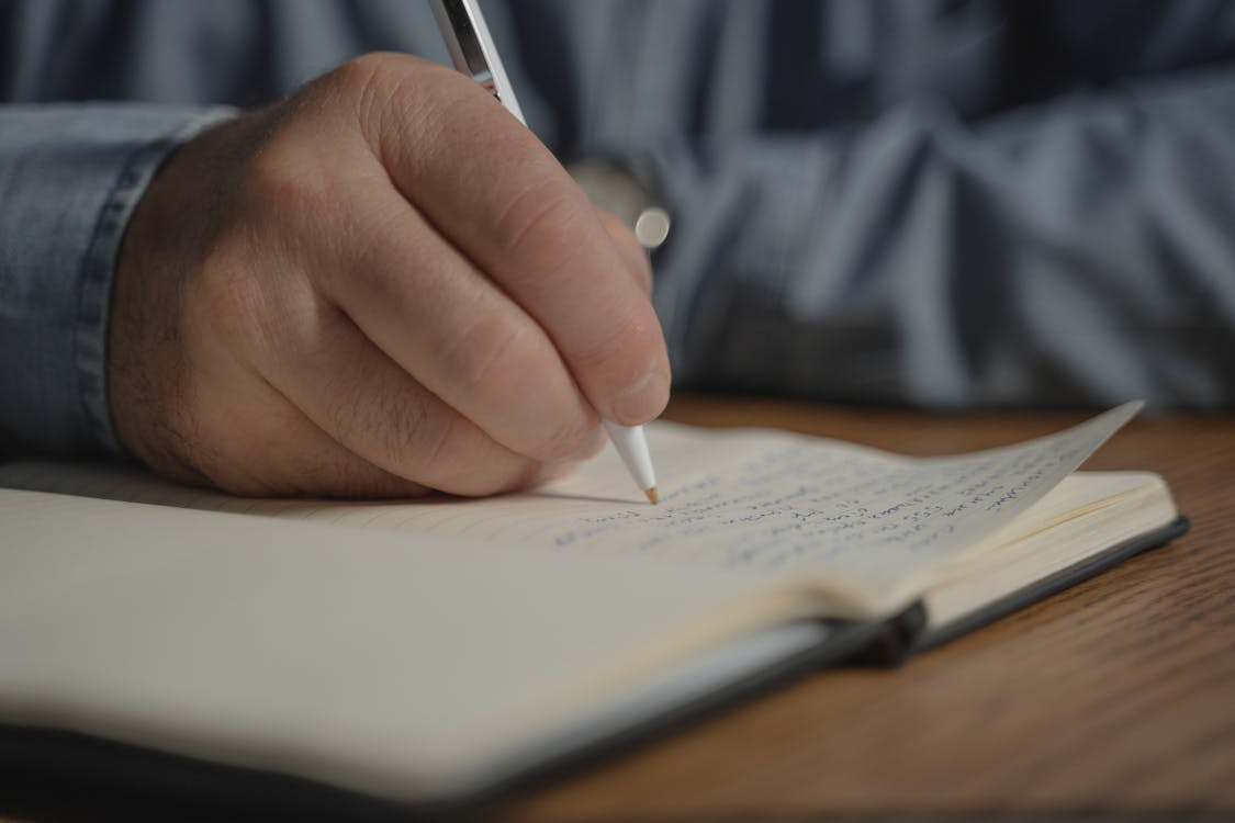 A close-up of open hands holding a small notebook with handwritten notes