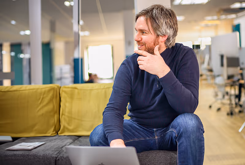 A man sitting on a couch with a laptop.