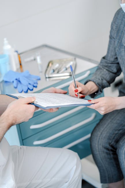 Patient signing healthcare agreement in doctor's office, focus on hands and document exchange.