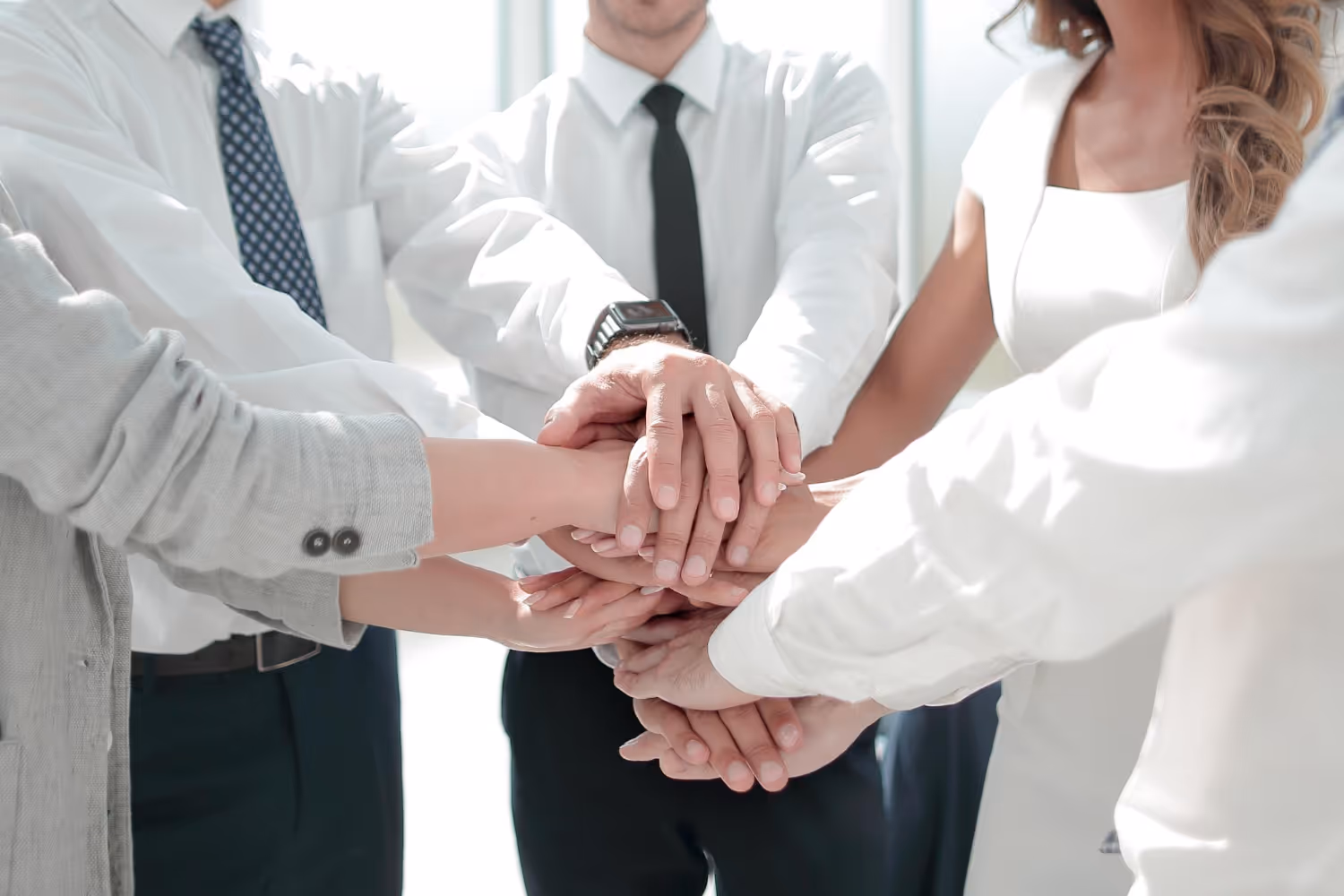 Grupa ludzi łącząca ręce w geście współpracy i jedności.