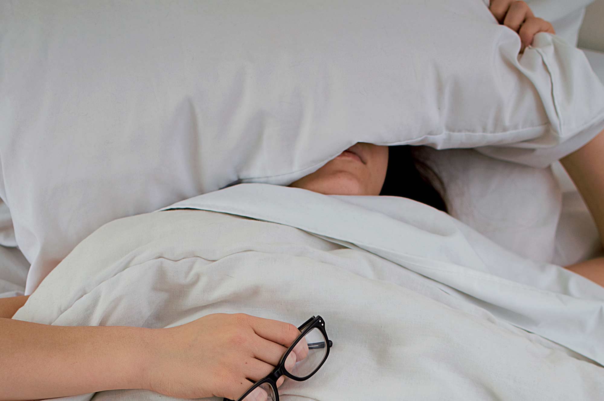A woman sleeping with a pillow over her eyes
