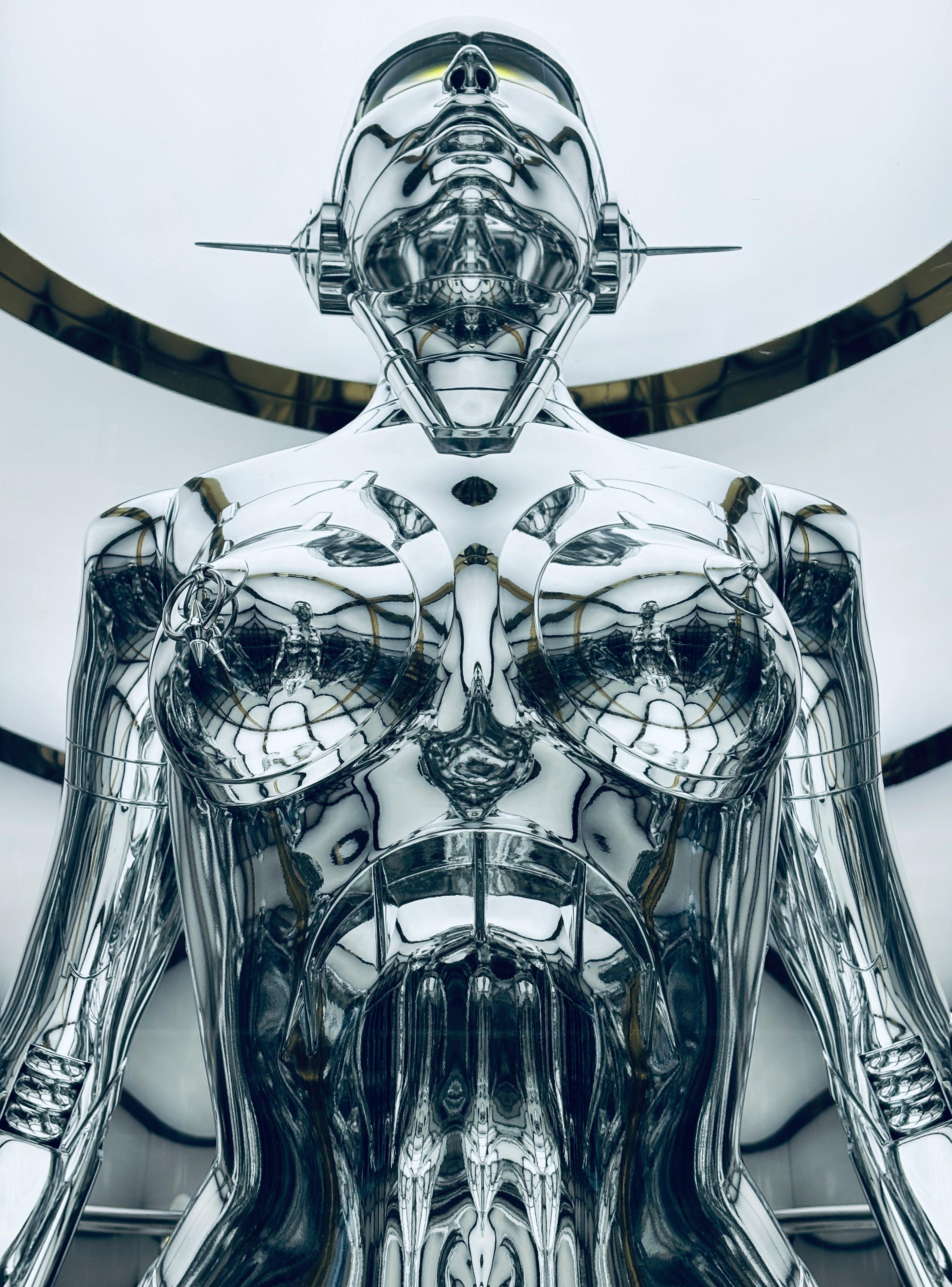 A close-up view of a metallic futurist robot sculpture indoors.