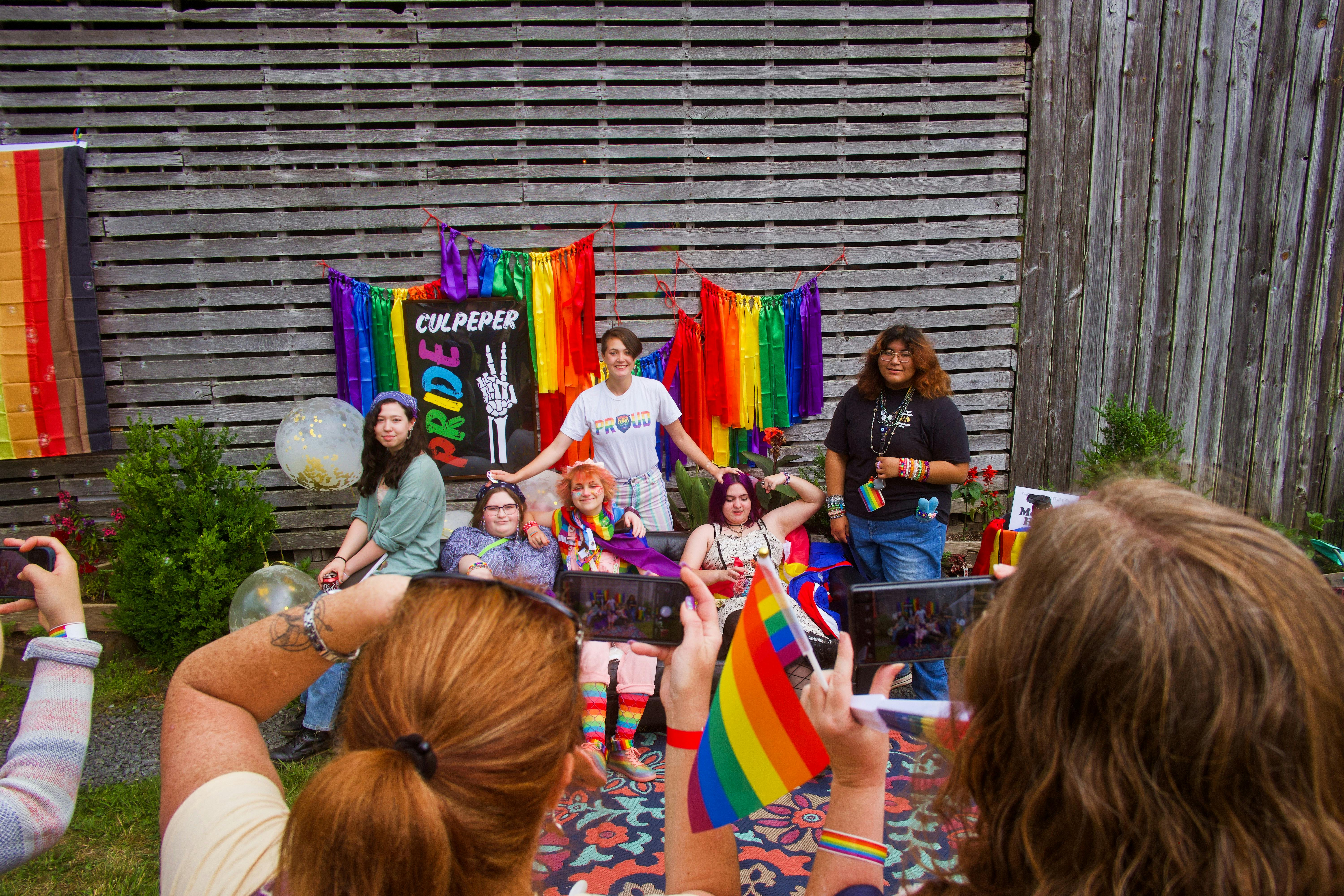 Group of diverse individuals celebrate Pride with colorful flags and joyful smiles outdoors.