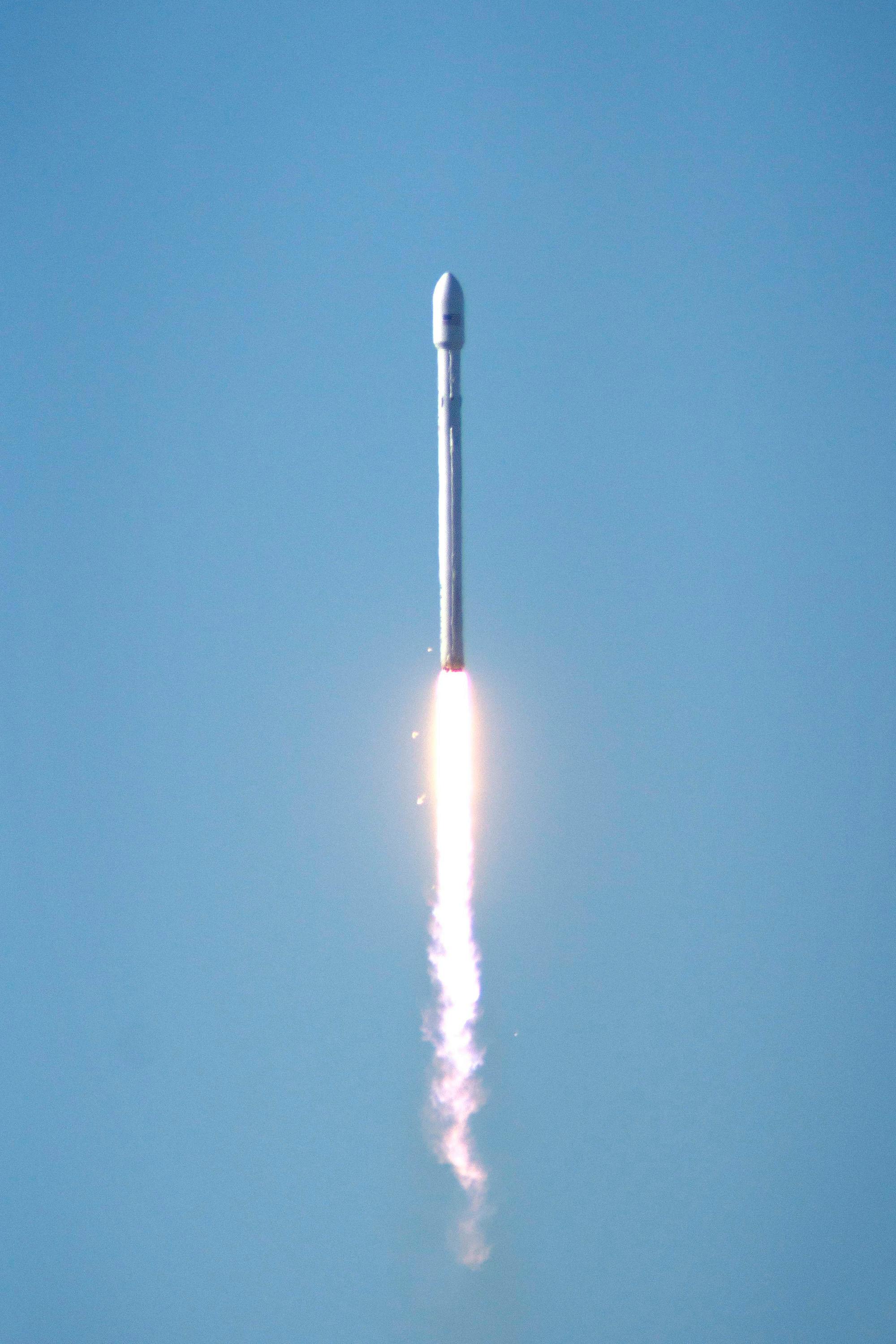 Falcon 9 rocket launching into space, showcasing powerful propulsion against a clear blue sky.