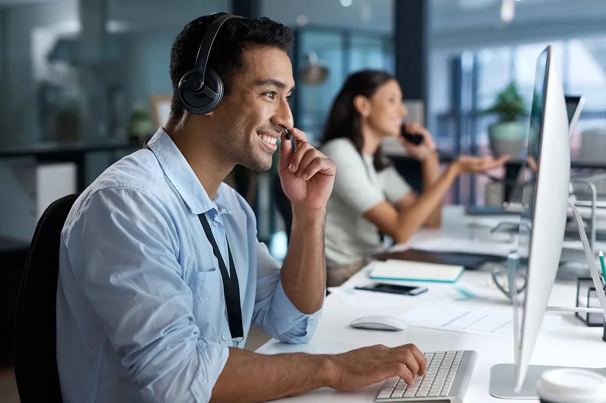 A man working as a tech support employee with woman coworker in the background