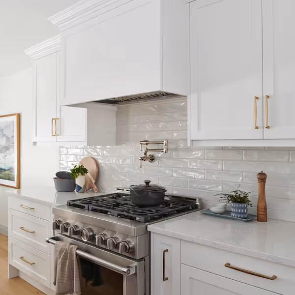 White kitchen cabinetry with glass upper cabinet doors, a counter with a coffee maker, and a wine cooler beneath the counter on a wooden floor.