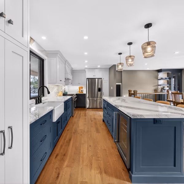 White kitchen cabinetry with glass upper cabinet doors, a counter with a coffee maker, and a wine cooler beneath the counter on a wooden floor.