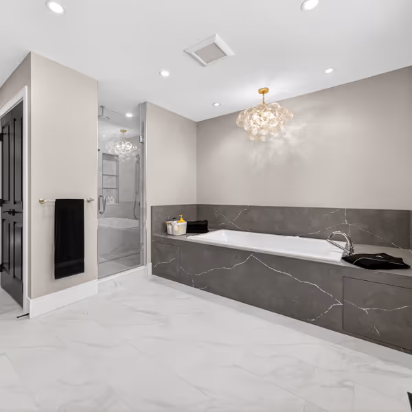 Modern kitchen shelving with wooden floating shelves displaying glassware, a small framed photo, bowls, a decanter, and flowers, above a countertop and wooden cabinets, with a dining table and chairs in the foreground.