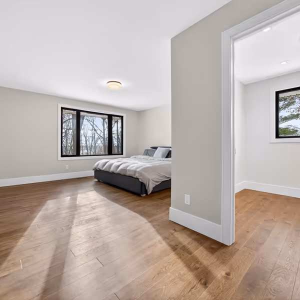 Modern living room corner with a gray sofa adorned with patterned pillows, a wooden shelf with decorative items, and a lit fireplace with a textured gray wall.
